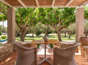 普拉基亚斯Fedra Plakias的树木繁茂的庭院里摆放着木桌和椅子