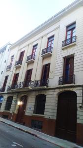 蒙得维的亚Posada Del Gaucho的白色的建筑,设有窗户和阳台,位于街道上