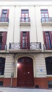蒙得维的亚Posada Del Gaucho的一座带红色门和阳台的建筑