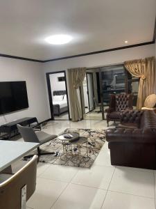 约翰内斯堡2Bedroom Luxury hotel apartment Fourways的客厅配有真皮沙发和电视
