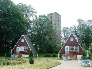 塔勒Ferienpark Rosstrappe的城堡前两个红色谷仓,配有桌椅