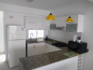 蓬塔赫尔莫萨Departamento en Punta Hermosa con Vista al Mar的厨房配有白色橱柜和白色冰箱。