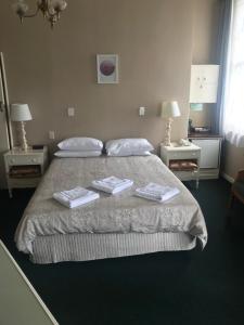 旺阿雷Grand Hotel - Whangarei的一间卧室配有一张床,上面有两条毛巾