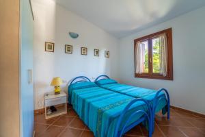 圣特奥多罗House in San Teodoro among the scents of Sardinia的一间卧室配有一张带蓝色床单的床和一扇窗户。