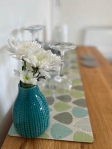 西卢港Penwyn Bed and Breakfast的绿花瓶,桌子上放着白色花