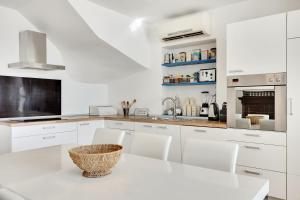 伊佐拉Vila Adriana的白色的厨房配有白色的桌子和椅子