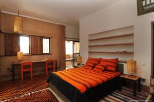 塔鲁丹特Dar al Hossoun的一间卧室配有一张带橙色枕头的床和一张书桌