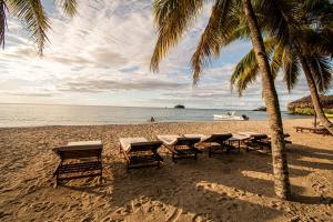 安迪拉纳Andilana Lodge的棕榈树海滩上的一组桌子