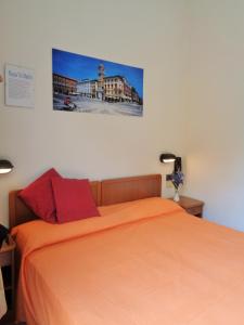 里米尼Hotel Lariana的一间卧室配有一张带橙色床单的床,墙上挂着一张照片