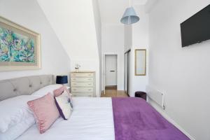 阿洛厄Craig Leith Apartment的卧室配有白色床和粉色及紫色枕头