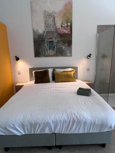 赫伦塔尔斯Whaaw Herentals的卧室配有一张白色床,墙上挂有绘画作品