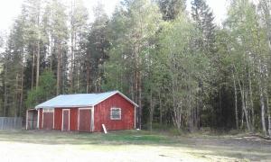 ÖverkalixVilla Polarktis的森林前方带蓝色屋顶的红色谷仓
