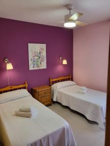 努瓦洛斯Casa Rural Reyes的紫色墙壁客房的两张床