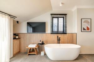 耶路撒冷Albi Boutique Hotel - Traveler's Choice 2024的一间带白色浴缸的浴室和一台电视机