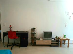 KonizopíQuiet, colourful home in Cyclades的客房设有书桌、电视和椅子。