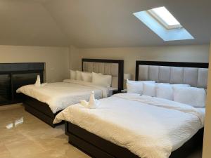 拉马拉Mizirawi Historic Hotel的一间卧室配有两张带白色床单的床和天窗。
