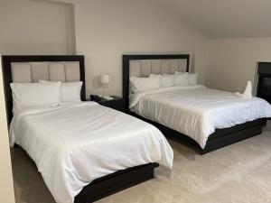 拉马拉Mizirawi Historic Hotel的卧室内的两张床,配有白色的毯子和枕头