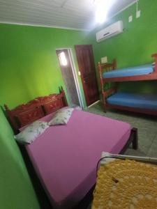 大普拉亚Pousada/suites Praia Grande III的绿色墙壁客房内的紫色床