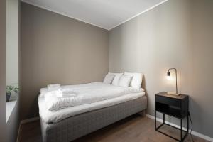 卑尔根Stay Nygård - Serviced apartments in central Bergen的一间小卧室,配有一张带白色床单和一盏灯的床