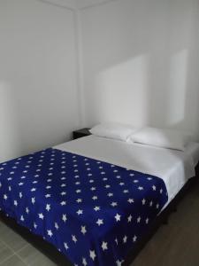 萨帕托卡La Casa de Mamá Tere的一张床上铺有蓝色毯子,上面有白色的星星