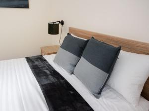 布里斯班Inala Hotel的卧室内的一张带三个枕头的床