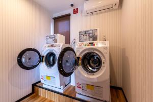 佐贺市HOTEL R9 The Yard Kohoku的客房内的2台洗衣机和干衣机