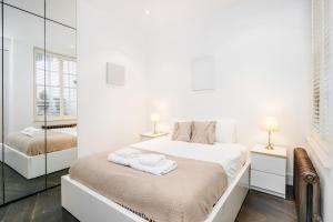 伦敦Beautiful 2 bedroom Covent Garden apartment的一间白色卧室,配有两张床和镜子
