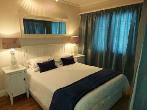 克尼斯纳Belle View @ Knysna Quays的卧室配有一张带蓝色窗帘的大型白色床