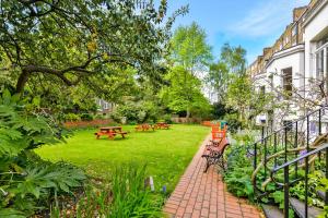 伦敦Lee Abbey London的草地上设有长椅和桌子的公园