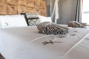 塞斯瑞姆Desert Homestead Lodge的一张带两张毯子和毛巾的白色床