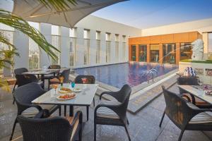 纳威孟买皇家兰花孟买中央格拉齐亚酒店的一间带游泳池和桌椅的餐厅