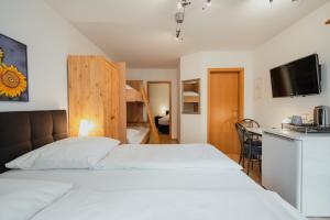 鲁斯特Park Hotel & Gästehaus Rust的卧室配有白色的床和电视。
