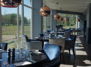 绍斯波特福姆比厅高尔夫度假酒店及水疗中心的用餐室设有桌椅和窗户。