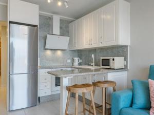 桑蒂亚戈德尔泰德Cosy Seaview Apartment的厨房配有白色橱柜、冰箱和凳子