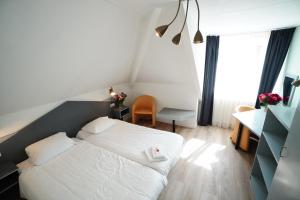 登堡Hotel Brasserie Den Burg的一间小卧室,配有白色的床和一张书桌