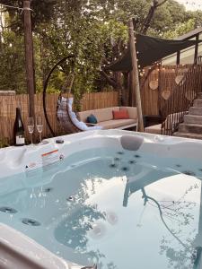 尼姆Maison dans les Arbres, SPA, Tennis, Parking的后院的按摩浴缸,提供一瓶葡萄酒