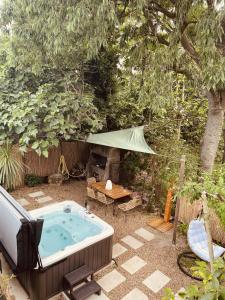 尼姆Maison dans les Arbres, SPA, Tennis, Parking的后院的热水浴池,配有桌子和帐篷