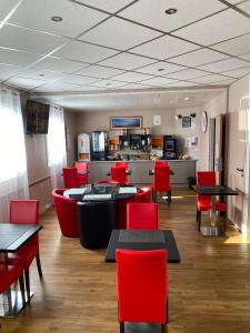 塞纳河畔罗米伊L'Hôtel du Marais Romilly Centre的一间带红色桌椅的用餐室和一间厨房