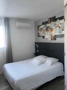 塞纳河畔罗米伊L'Hôtel du Marais Romilly Centre的卧室配有一张铺有白色床单的床,墙上挂着鲜花。