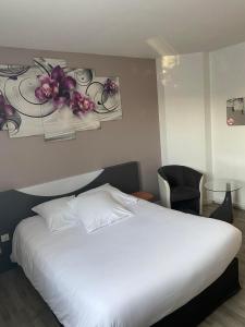 塞纳河畔罗米伊L'Hôtel du Marais Romilly Centre的卧室配有白色的床,墙上挂着鲜花