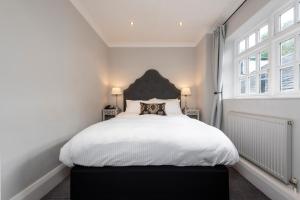 沃灵顿斯坦森洛奇酒店的一间卧室配有一张白色的床和黑色床头板