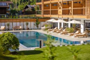 斯图姆Natur Resort RISSBACHER的酒店设有带椅子和遮阳伞的游泳池