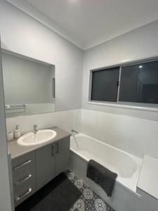 汤斯维尔Spacious 4 Bedroom House的带浴缸、水槽和镜子的浴室