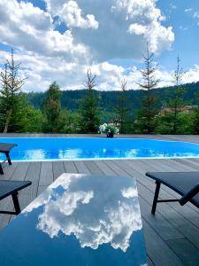布克维Шале БІЛИЙ ЛЕВ - WHITE LION Chalet的一座游泳池,在桌子上映着天空