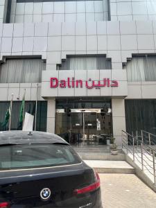 利雅德Dalin Hotel的停在大楼前的带有标志的汽车