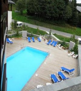 莱热Appartement 2 pièces Résidence les Fermes Emiguy Les Gets的一个带蓝色躺椅和一系列家具的游泳池