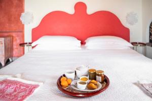 CarascoVilla Paggi Country House的床上的盘子,上面有杯子和橙子