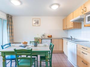 拉卡诺奥肯Apartment Village Cheval Spa Résidences-4 by Interhome的带绿椅的桌子的厨房和带水槽的厨房