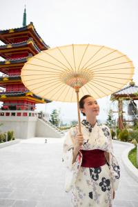 岘港Da Nang - Mikazuki Japanese Resorts & Spa的身穿和服的女人,拿着伞
