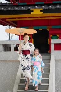 岘港Da Nang - Mikazuki Japanese Resorts & Spa的一名妇女和一名儿童在楼梯上手持雨伞